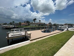 Un puerto deportivo con muelles, una zona verde y casas al fondo.