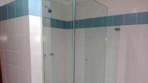 Una cabina de ducha con paredes de azulejos blancos y una franja azul.