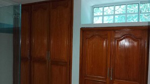 Una habitación con dos armarios de madera y un ventanal con vistas a árboles.