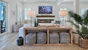 A spacious living room with a fireplace, a ceiling fan, and a large window.