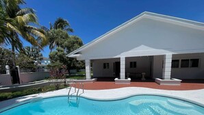 Una piscina con una casa blanca al fondo.