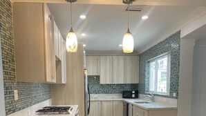 Una cocina moderna con una isla de madera, dos lámparas colgantes y un microondas integrado.