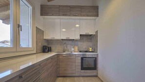Una cocina moderna con armarios de madera, horno empotrado y cafetera.