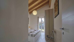 Un dormitorio con cama, lámpara colgante y vista al exterior.