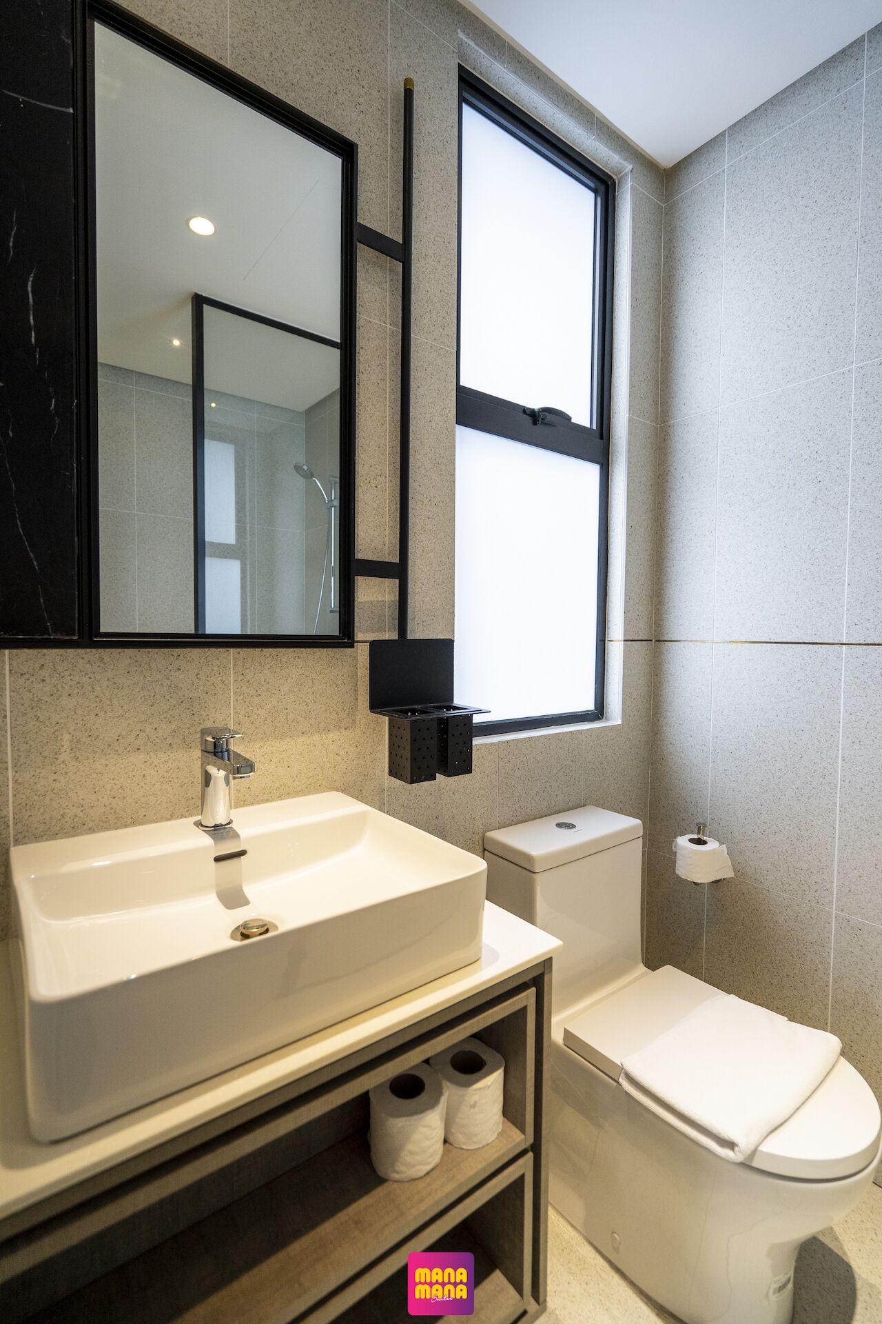 A modern bathroom with a large sink, toilet, and a mirror above the sink.