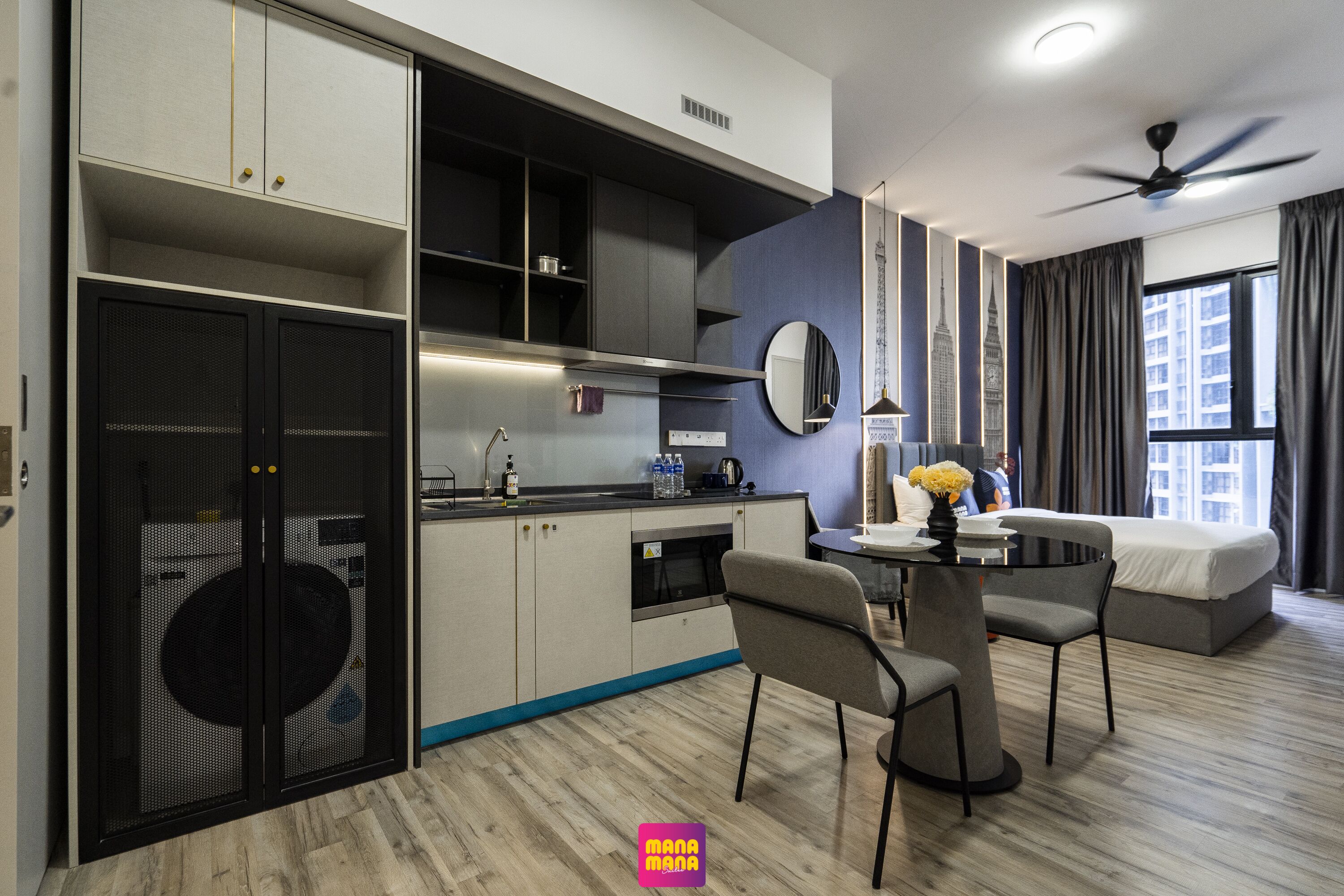 A modern hotel room with a dining area, kitchenette, and a bed.