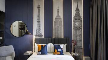 A hotel room with a bed, a round mirror, a chair, and a nightstand with a lamp.