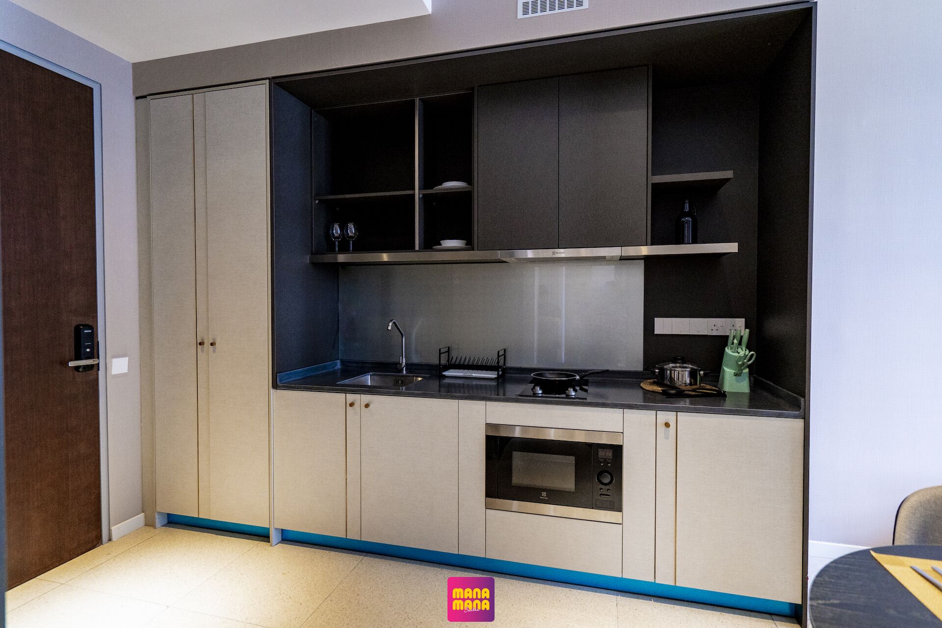 Una cocina compacta con horno empotrado, un lavamanos y un microondas.