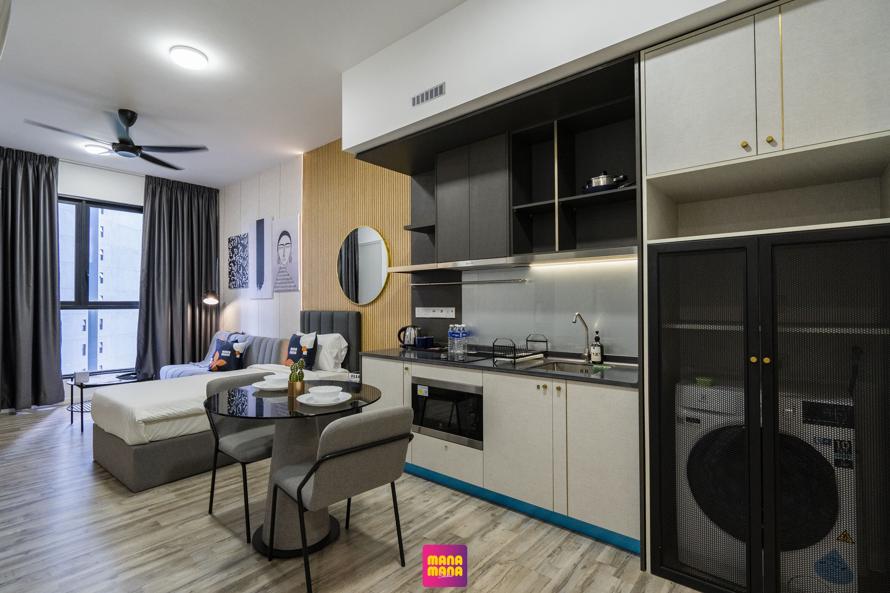 Una habitación de hotel moderna con kitchenette, zona de comedor, sofá y un amplio ventanal.