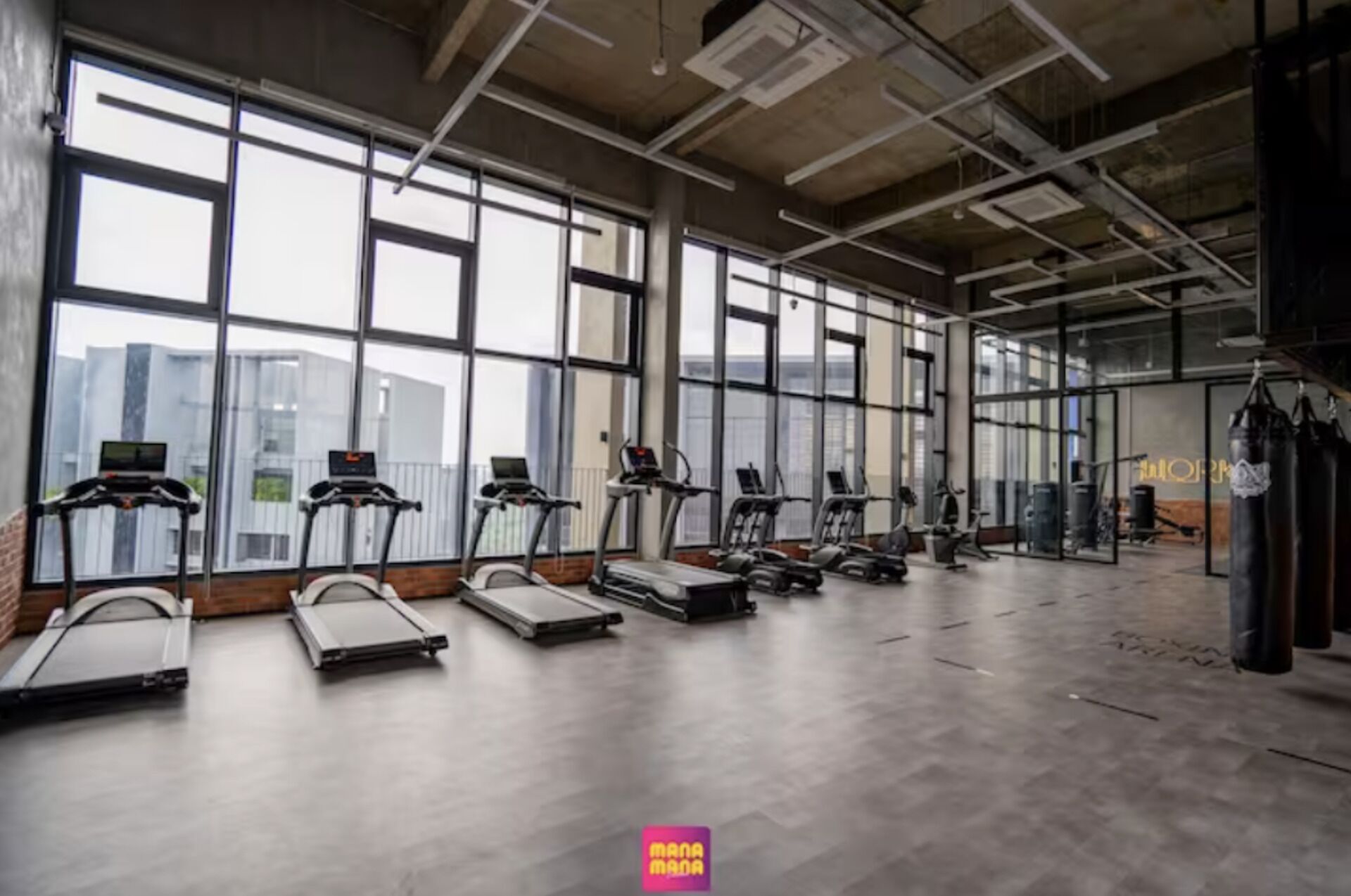 A gym with treadmills, stationary bikes, and punching bags.