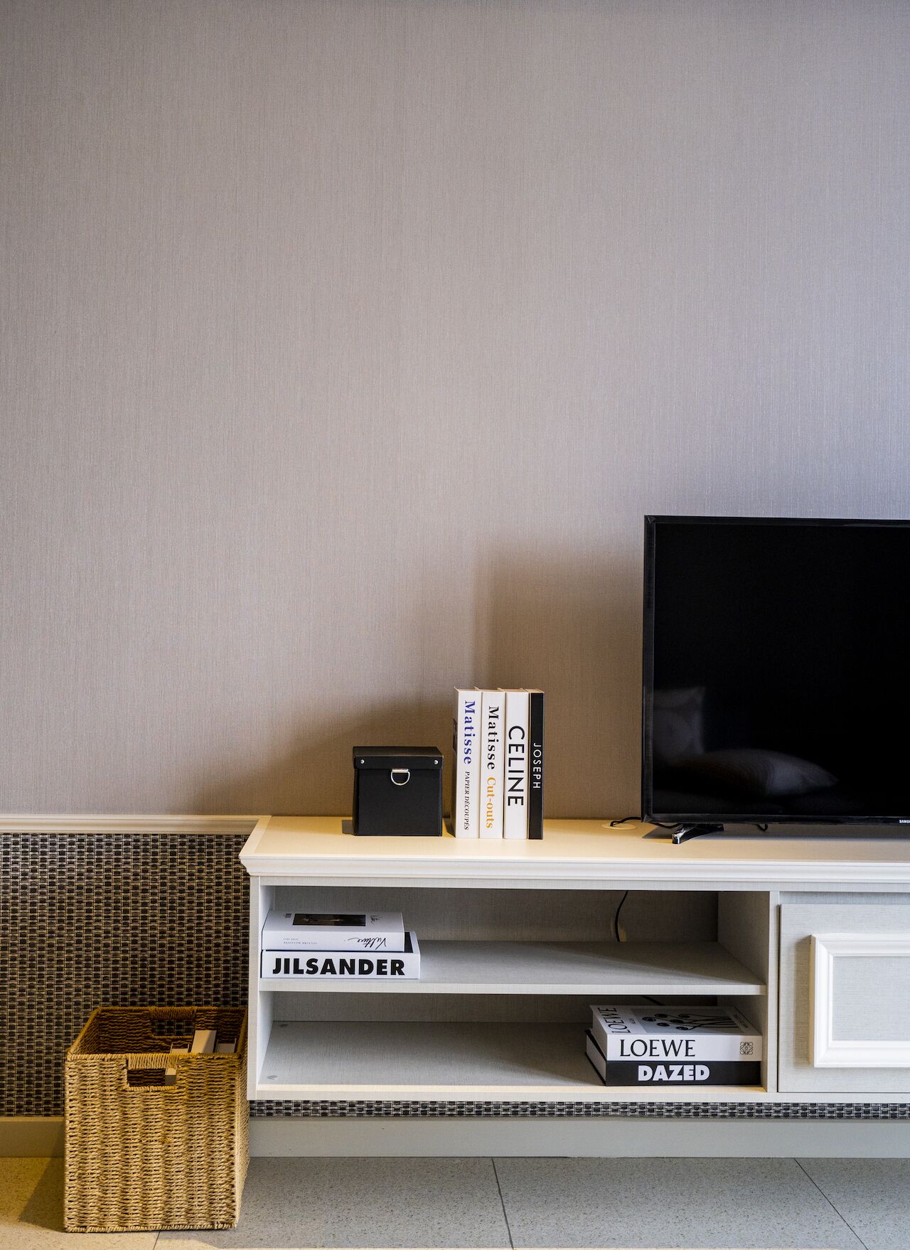 Un saló amb televisió, una estanteria plena de llibres i una cistella de vimet.
