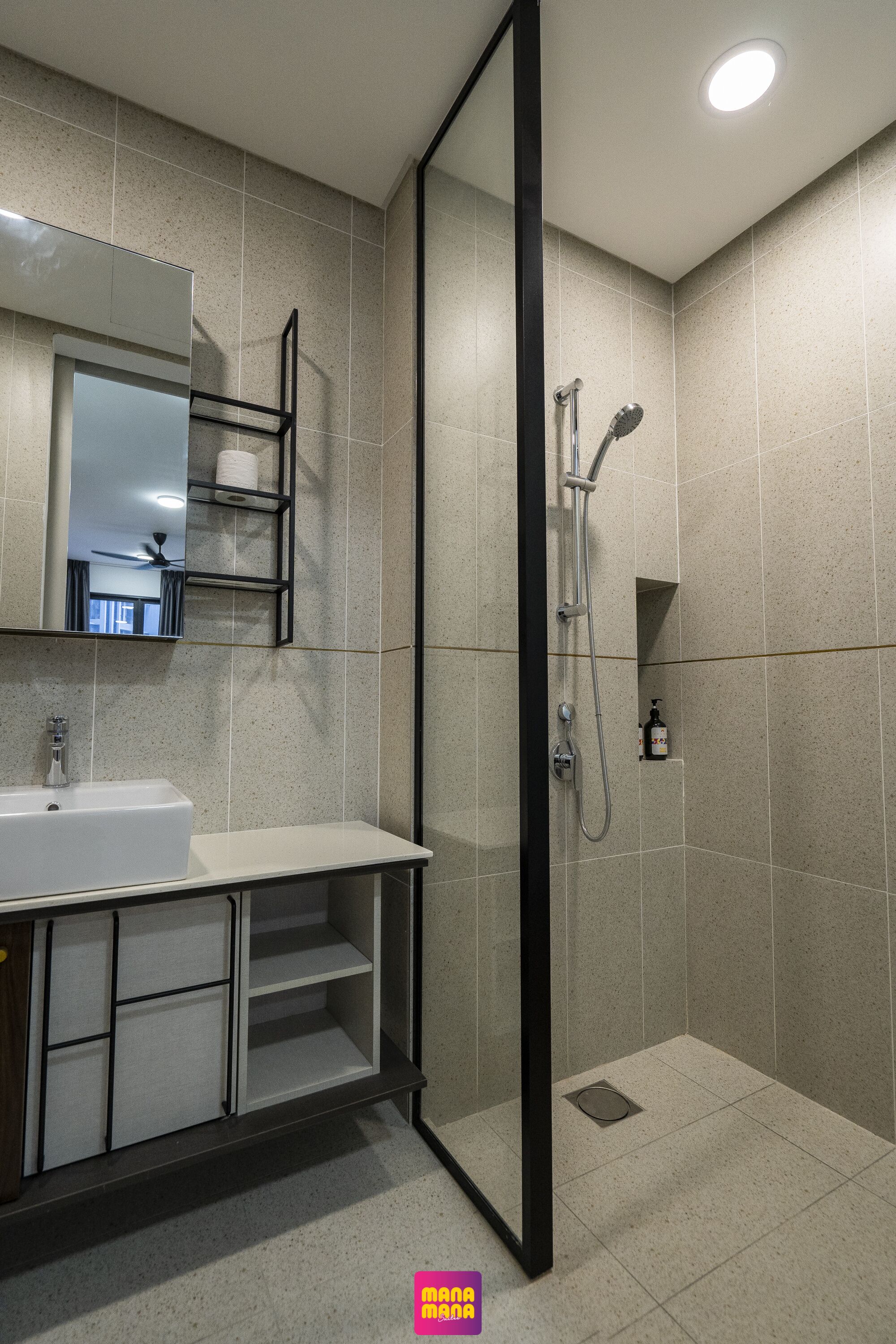 Un baño moderno con ducha de mampara de vidrio, lavamanos y espejo.