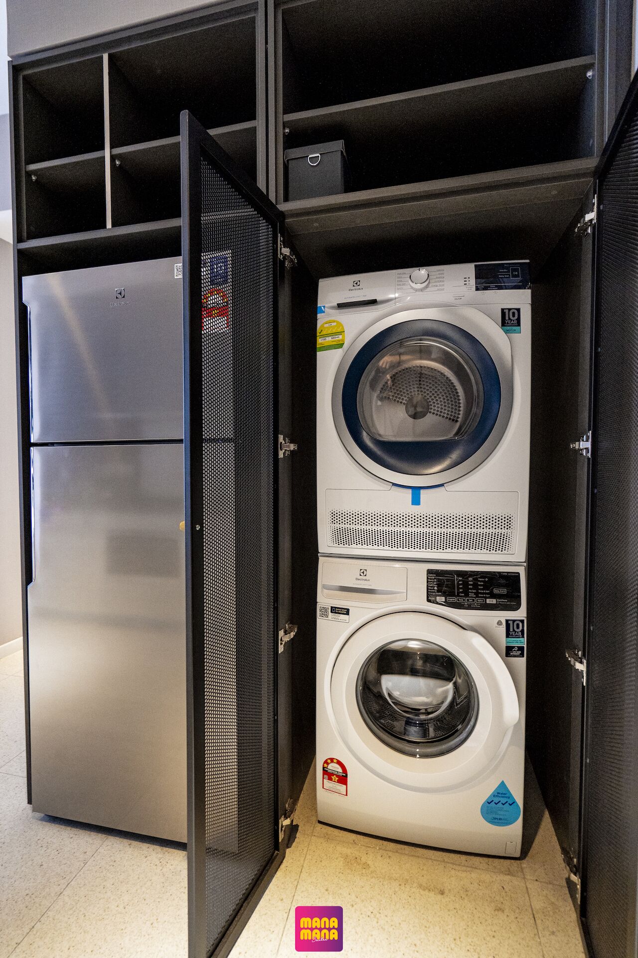 A compact washer and dryer unit with a 10-year warranty sticker, placed in a small, enclosed space with a metal mesh door.