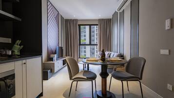 A modern kitchen with a dining area, a television, and a view of the city.
