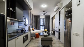 Une chambre d’hôtel compacte comprenant un coin cuisine, un lit, un espace repas et une salle de bain.