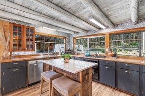 Una cucina moderna con isola centrale, mobili in legno e ampie finestre che danno sulla foresta.