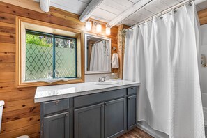 A bathroom with wooden walls, a white sink, and a shower curtain. - -River Retreat Log Cabin w/ Gym, Game Room, and Sauna- (Jacksonville)