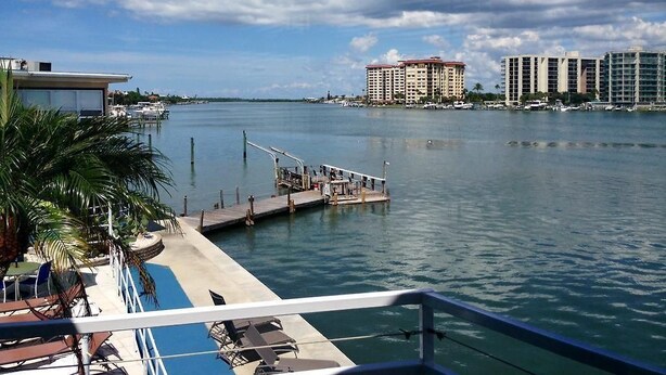 A marina with a dock, a pool area, and a view of a cityscape with high-rise buildings.