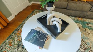 Une table ronde blanche surmontée d’un plateau noir, un chandelier blanc agrémenté d’une plante et un livre intitulé « Histoire méconnue de Memphis ».