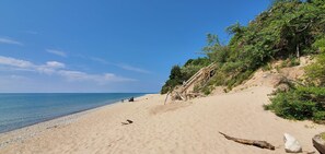 A beach with a wooden staircase leading up a sandy slope, a clear blue sky, and calm sea. - Red Shutters Rustic Cottage CSA Private Community (Frankfort)