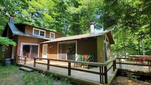 Une cabane en bois dotée d’une terrasse, d’un porche couvert et d’une cheminée.