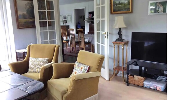 A living room with two armchairs, a television, and a dining area in the background. - Relaxing holiday in quiet surroundings (Frederikshavn)