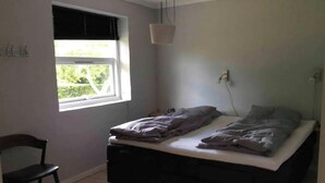 A bedroom with a single bed, a chair, a window with blinds, and a hanging light fixture. - Relaxing holiday in quiet surroundings (Frederikshavn)