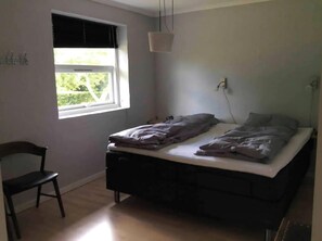 A bedroom with a single bed, a chair, a window with blinds, and a hanging light fixture. - Relaxing holiday in quiet surroundings (Frederikshavn)