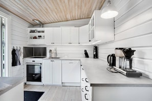 A modern kitchen with white cabinetry, a built-in oven, a dishwasher, and a coffee maker. - 3 bedroom accommodation in Hundested (Hundested)