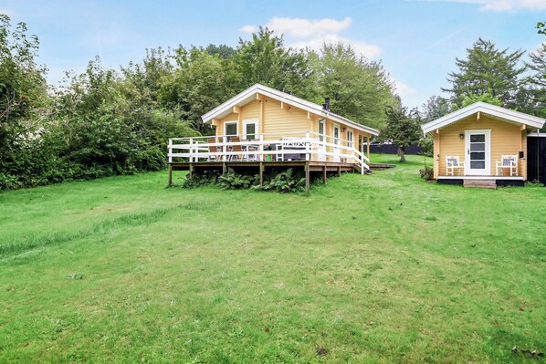 A yellow house with a deck and a smaller adjacent structure.