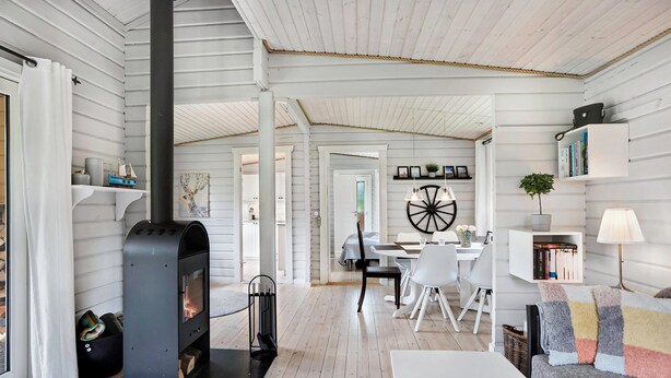 Un interior acogedor con chimenea, paredes blancas, un comedor y una estantería.