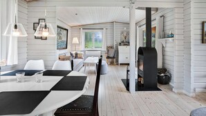 Una habitación con mesa de comedor, sillas, sofá, chimenea y vistas al exterior.