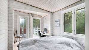 Un dormitorio con cama, escritorio con computadora y ventana.