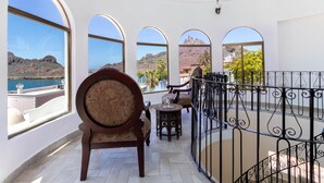 A balcony with a view of a mountainous landscape and a body of water.