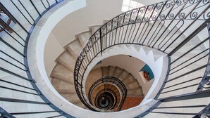 A spiral staircase with a metal railing and beige steps.