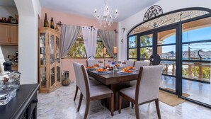 A dining area with a wooden table set for four, surrounded by chairs. A large window offers a view of the outdoors.