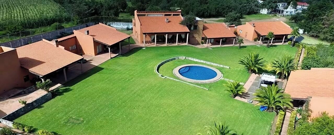 Il s’agit d’une propriété résidentielle dotée d’une piscine, de plusieurs maisons et d’une pelouse bien entretenue.