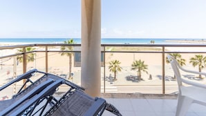 Un balcón con vistas a la playa, palmeras y un cielo despejado.