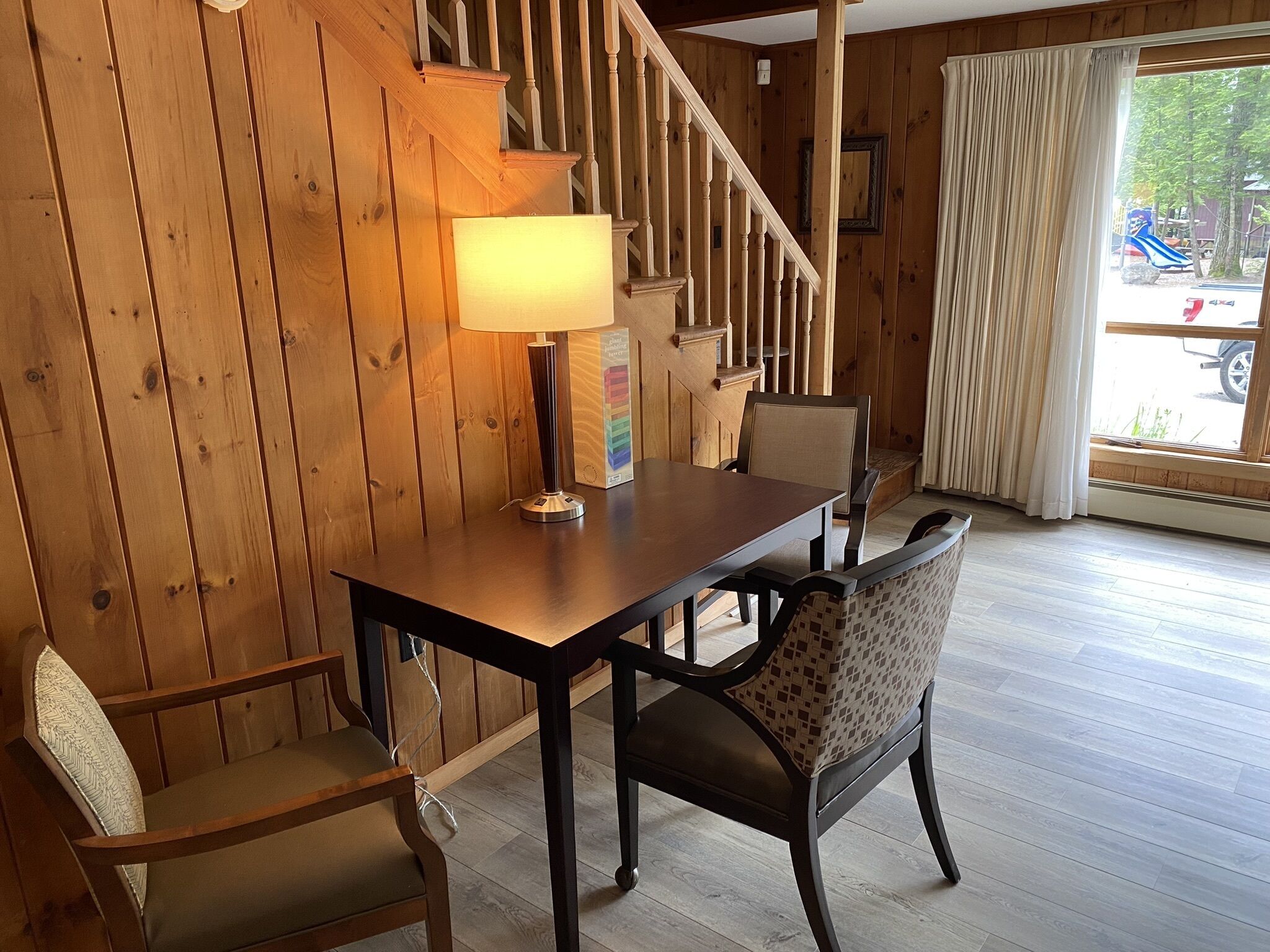 Un intérieur en bois comprenant une table et des chaises, une lampe et un escalier.