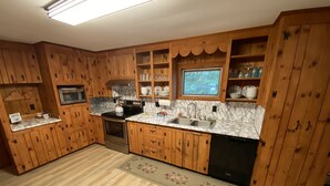 A kitchen with wooden cabinets, a microwave, a stove, a sink, and a window.