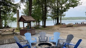 A lakeside seating area with Adirondack chairs and a fire pit.