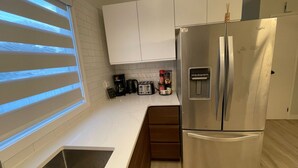 A modern kitchen with white cabinets, a stainless steel refrigerator, a built-in oven, a coffee maker, and a toaster. - Beautiful and Spacious 3 BDR/3 Beds Home (Winnipeg)