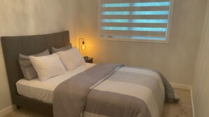 A neatly made bed with a grey and white striped duvet, a grey headboard, and a bedside lamp. - Beautiful and Spacious 3 BDR/3 Beds Home (Winnipeg)