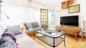 Un salon bien éclairé, avec un canapé, une table basse et un téléviseur.