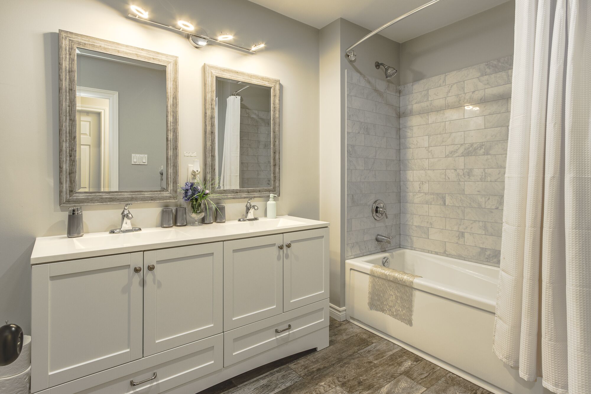 A bathroom with a double vanity, two mirrors, a shower with a glass door, and a bathtub.