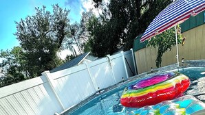 Una piscina con tobogán, flotador y escalera.