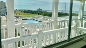 Zona de piscina con vista al océano, un pabellón y una valla blanca.