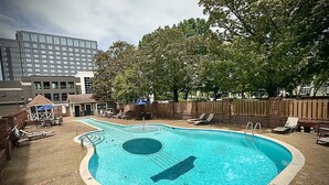 A swimming pool with lounge chairs and a wooden fence.