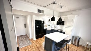 A modern kitchen with white cabinetry, a black refrigerator, and a central island with bar stools.