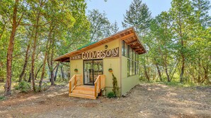 A small cabin with a wooden deck and a sign that reads "GOODVIBES ONLY". - Breathtaking River Retreat RV Campground - Gym, Game Room, Sauna (97530, Jacksonville, OR)